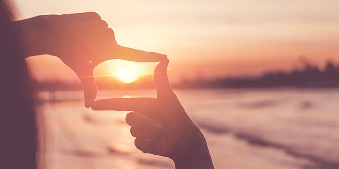 Hands framing a sunset, symbolising vision and focus for a target operating model.